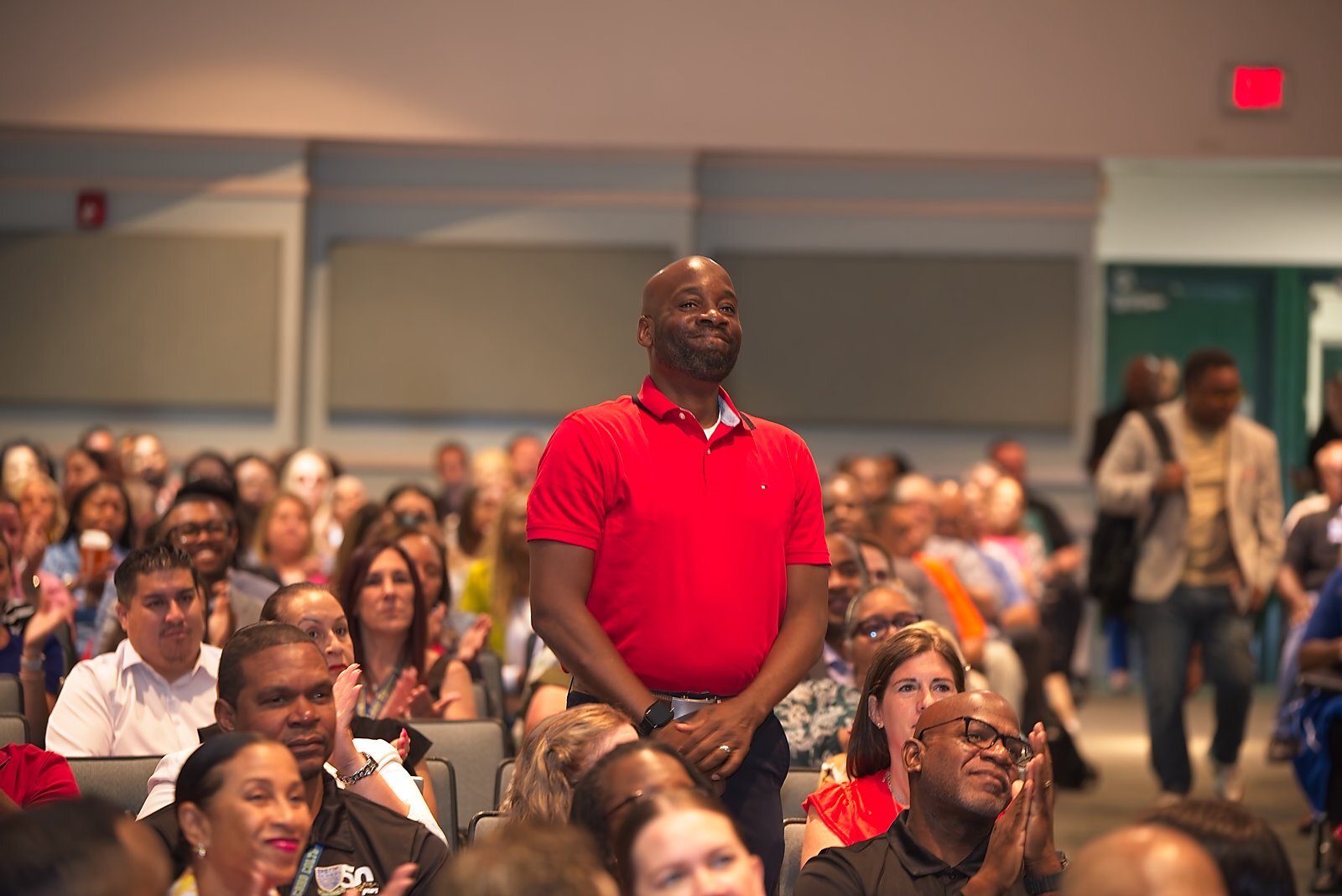 An administrator recognized, standing to applause during a general session