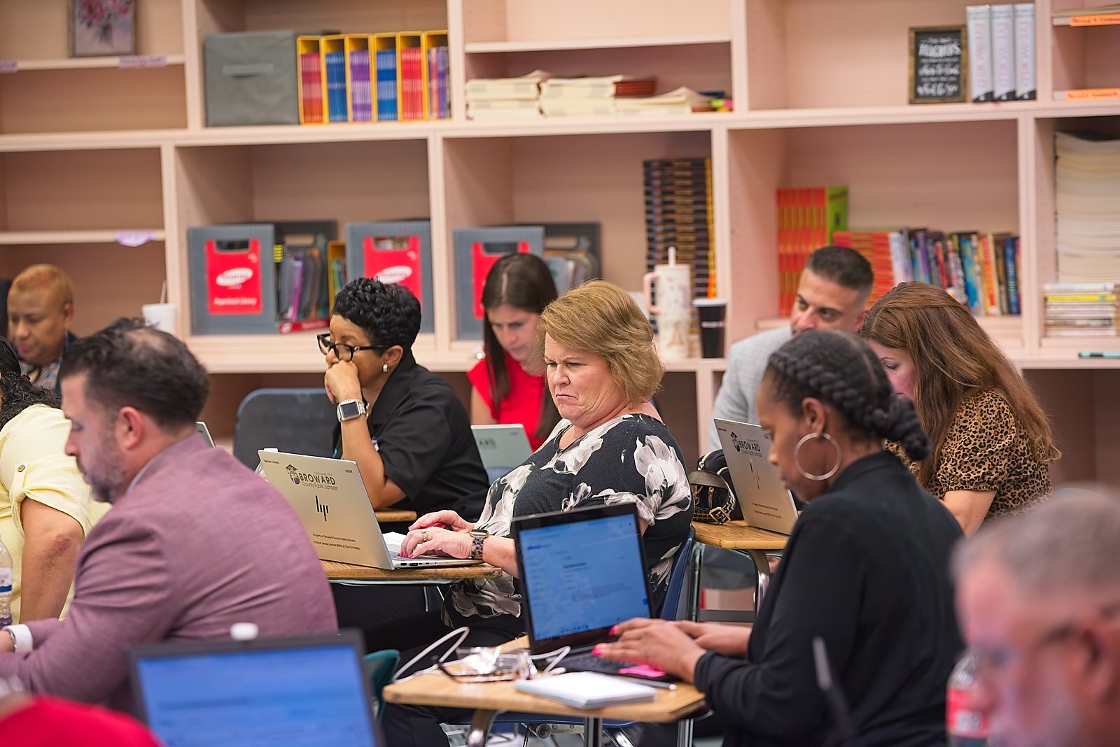 Attendees working on laptops during a breakout session, classroom library in the background